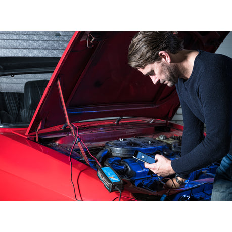 Victron Blue Smart IP65 charger connected to a car battery in a garage
